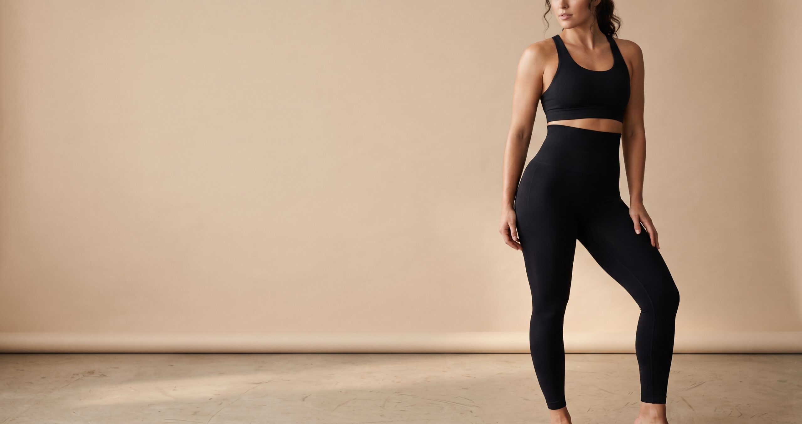 Mujer con mallas moldeadoras negras y top deportivo, banner principal.