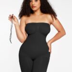 Mujer con body reductor negro sin tirantes sujetando un tirante, vista frontal.