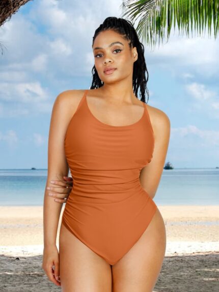 Mujer con bañador moldeador naranja fruncido en la playa.